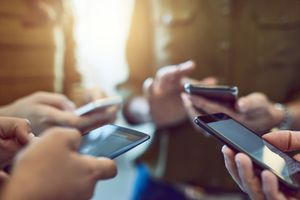 <p>Un groupe de quatre personnes tenant leur téléphone portable.</p>